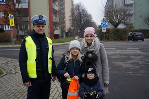 Policjant z drogówki obok dzieci i matki, którym wręczył odblask