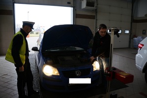 Policjant z drogówki obok kierowcy na stacji diagnostycznej