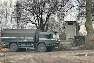 Samochód wojskowy patrol saperski na tle domów