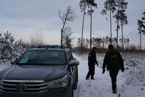 Policjant i straznik leśny na tle lasu i samochodu straży leśnej