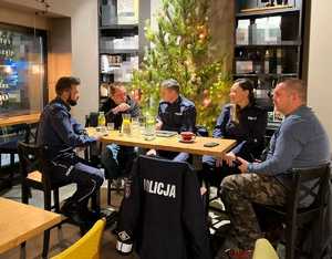 Przy stoliku siedzą policjanci z gośćmi