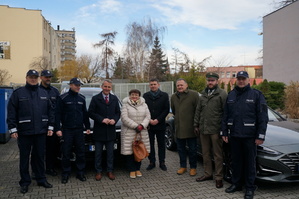 Wspólne zdjęcie policjantów z samorządowcami na tle dwóch nowych radiowozów