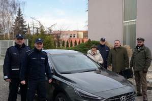 Policjanci i samorządowcy oraz leśniczy na tle radiowozu