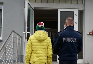 Zatrzymana kobieta na kradzieży sklepowej stoi przy policjancie
