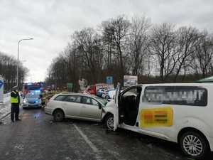 Widok dwóch pojazdów, które się zderzyły, rozbite samochody na środku drogi oraz policjant z drogówki w czasie czynności