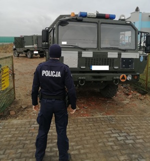 Policjant na tle wojskowego samochodu patrol saperski