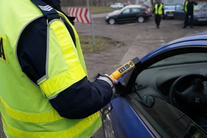 Policjant z drogówki z alkomatem przy samochodzie