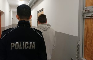 Zatrzymany włamywacz stoi obok policjanta