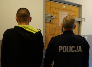 Policjant stoi obok zatrzymanego złodzieja