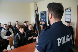 Policjant na sali odpraw rozmawia z uczniami ekonomika