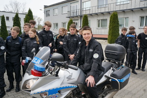 Uczniowie na placu komendy na tle policyjnego motocykla
