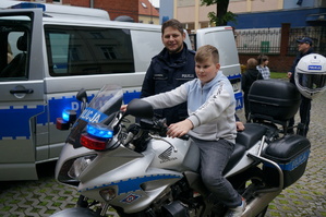 Dziecko na policyjnym motocyklu obok stoi policjant