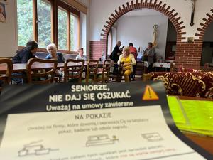 Widoczna ulotka dla seniorów a w tle seniorzy i policjanci