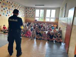 Policjant opowiada dzieciom o bezpiecznym spędzaniu czasu w czasie wakacji