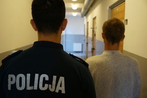 Policjant stoi obok młodego mężczyzny podejrzanego o kradzież roweru