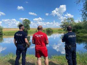 Na tle żwirowni policjanci i ratownik wodnego ochotniczego pogotowia ratunkowego