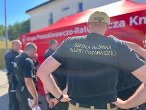 Strażacy i policjanci na tle namiotu