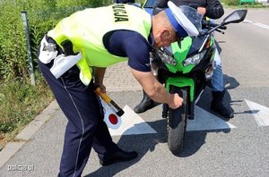 Policjant z drogówki sprawdza stan ogumienia w motocyklu