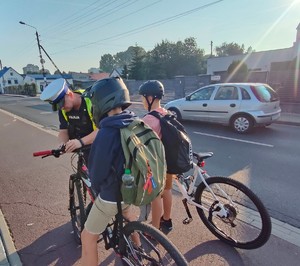 policjanci montują dzwonek chłopcom na rowerach