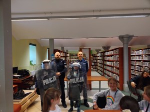 na zdjęciu policjanci i dzieci w przymierzające policyjne kamizelki i kaski