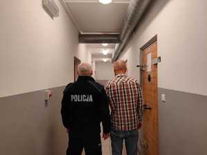 na zdjęciu zatrzymany mężczyzna tyłem z policjantem