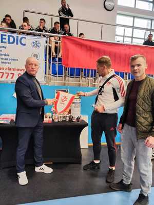 na zdjęciu komendant wkładają pieniądze do puszki