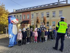 na zdjęciu policjant i przedszkolaki omawiają bezpieczeństwo