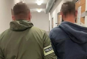 NA ZDJĘCIU POLICJANT KRYMINALNY Z ZATRZYMANYM STOJĄ TYŁEM