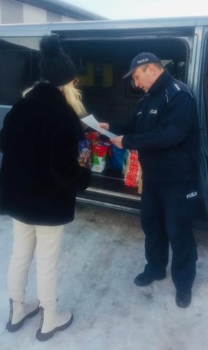 na zdjęciu policjant z kobietą z fundacji i bus z darami