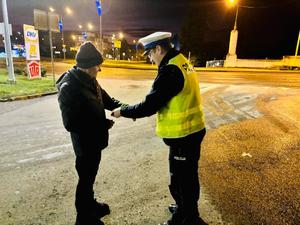 na zdjęciu policjant rozdaje odblaski