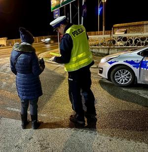 na zdjęciu policjant rozdaje odblaski