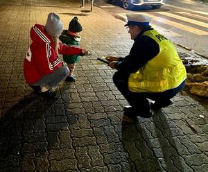 na zdjęciu policjant rozdaje odblaski dziecku