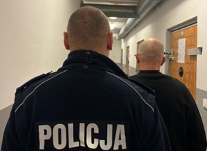 na zdjęciu sprawca z policjantem stoją tyłem