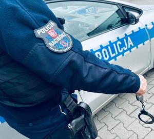 na zdjęciu policjant ruchu drogowego trzyma kajdanki