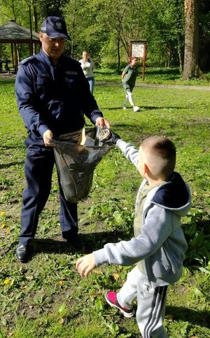 na zdjęciu chłopczyk wrzuca sieci do worka trzymanego przez policjanta