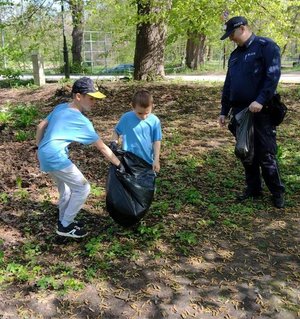 na zdjęciu Policjanci i dzieci sprzątają park