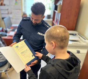 na zdjęciu policjant wręcza dyplom chłopczykowi