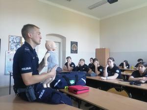 na zdjęciu policjant tłumaczy zasady pierwszej pomocy