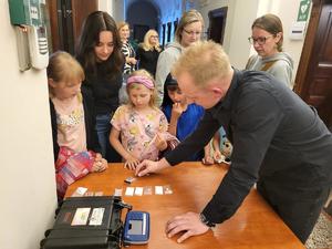 na zdjęciu policjant pokazuje jak się ściąga linie papilarne