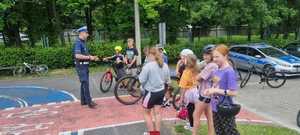 na zdjęciu dzieci ustawiają się aby przystąpić do egzaminu policjant tłumaczy zasady