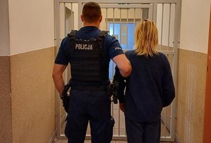 na zdjęciu zatrzymana kobieta z policjantem stoją tyłem