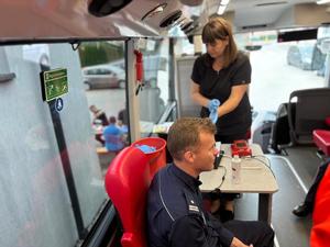 na zdjęciu policjant wypisuje kartę zgłoszenia w autobusie