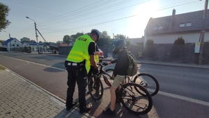 na zdjęciu policjant daje odblask rowerzystom