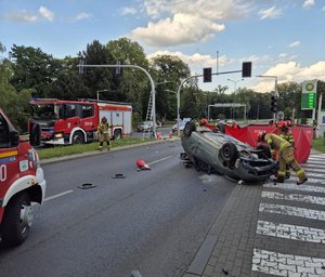 na zdjęciu widać strażaków i policjantów drogówki działających na miejscu zdarzenia pojazd jest na dachu