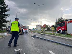 na zdjęciu widać strażaków i policjantów drogówki działających na miejscu zdarzenia pojazd jest na dachu oraz uszkodzoną latarnię