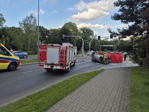 na zdjęciu miejsce zdarzenia drogowego pojazd znajduje się na dachu pracują na miejscu strażacy oraz ratownicy i policjanci