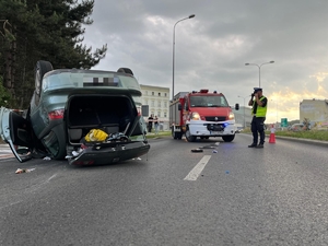 na zdjęciu pojazd na dachu a policjant ruchu drogowego robi dokumentację fotograficzną