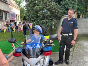 na zdjęciu policjant i chłopczyk siedzący na motocyklu