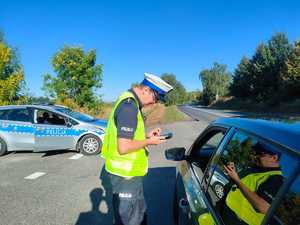 na zdjęciu policjant ruchu drogowego kontroluje pojazd