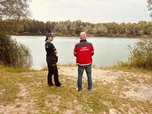 na zdjęciu policjantka i ratownik wopr kontrolują zbiorniki wodne